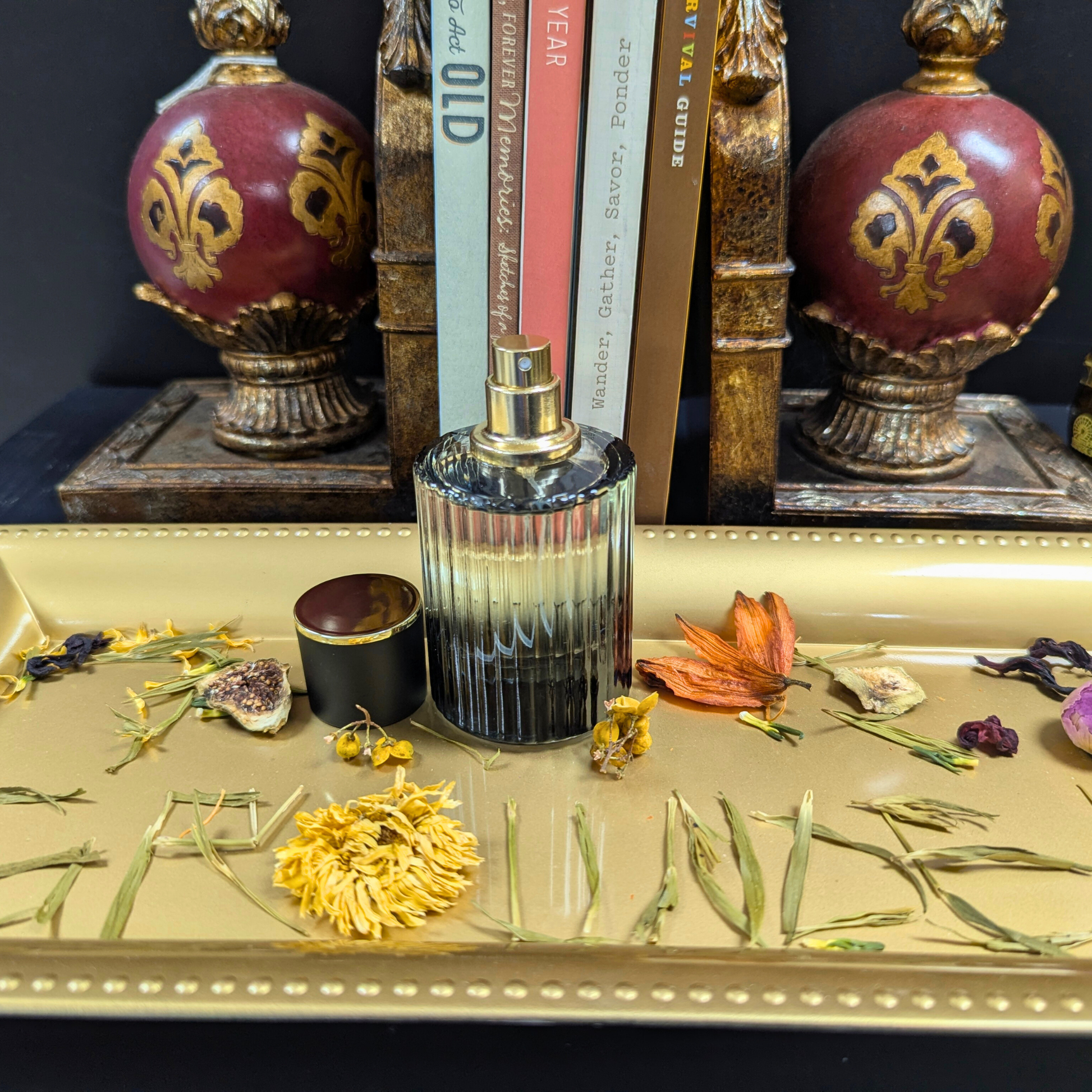 Decorative bottle with gold accents on a table with flowers and books in the background