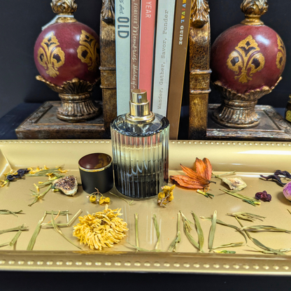 Decorative bottle with gold accents on a table with flowers and books in the background
