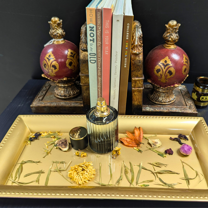 Decorative setup with ornate bottles, books, and a decorative tray with flowers and crystals on a dark surface.
