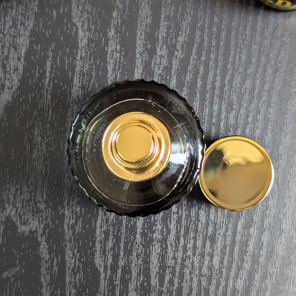 Black bottle cap with gold center on a gray surface