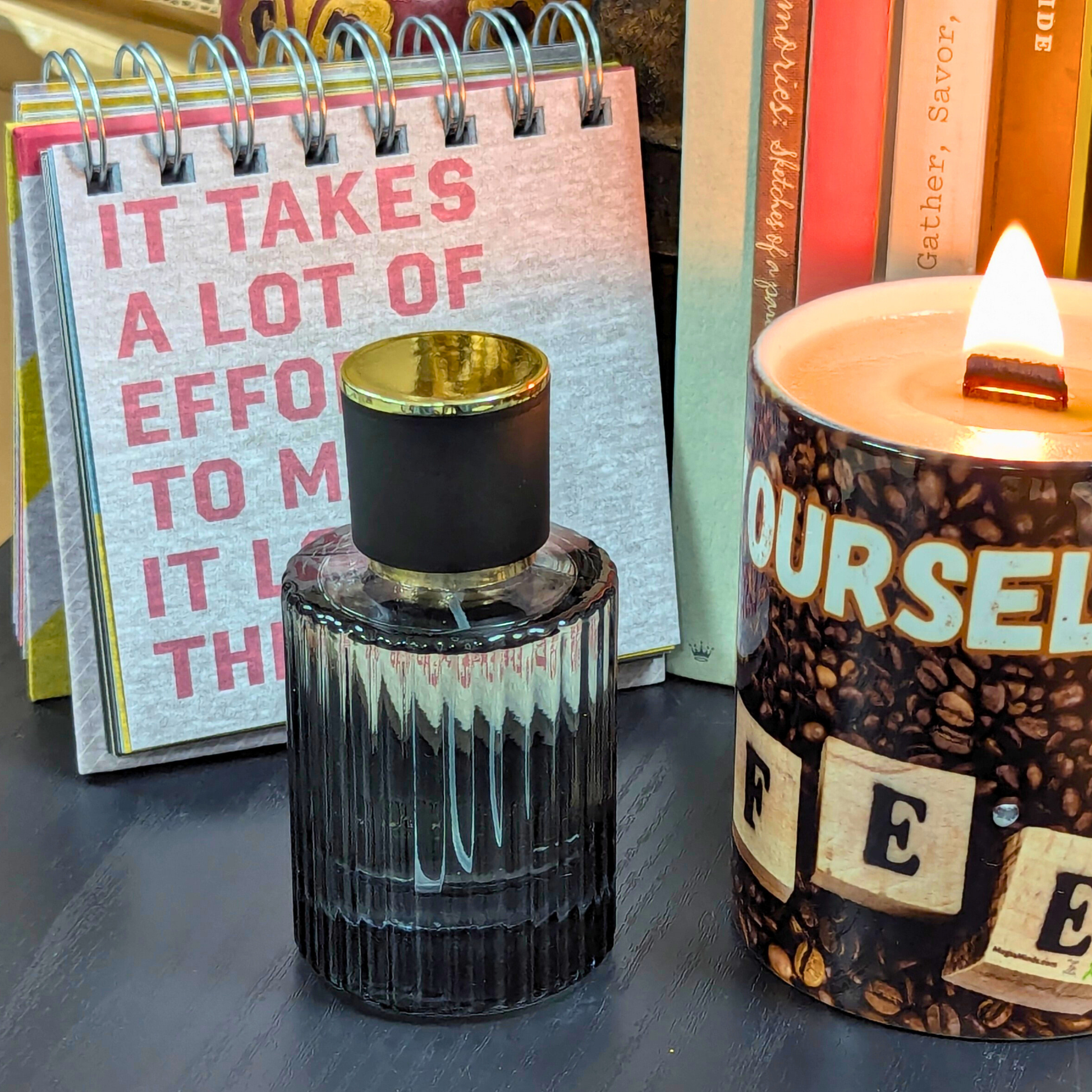 Perfume bottle and candle with motivational notebook in the background