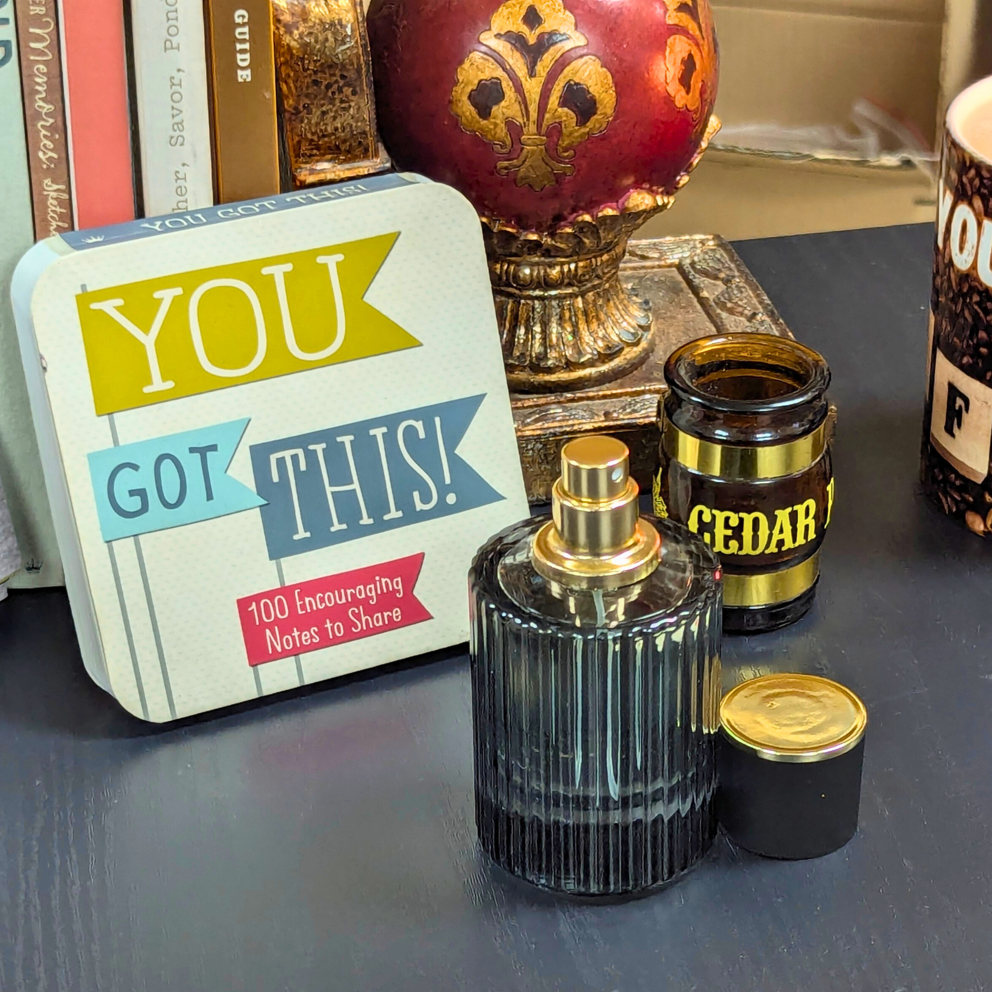 Perfume bottle, 'You Got This' card, and other items on a surface