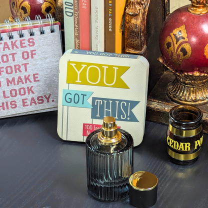 Perfume bottle with 'You Got This!' motivational card on a reflective surface